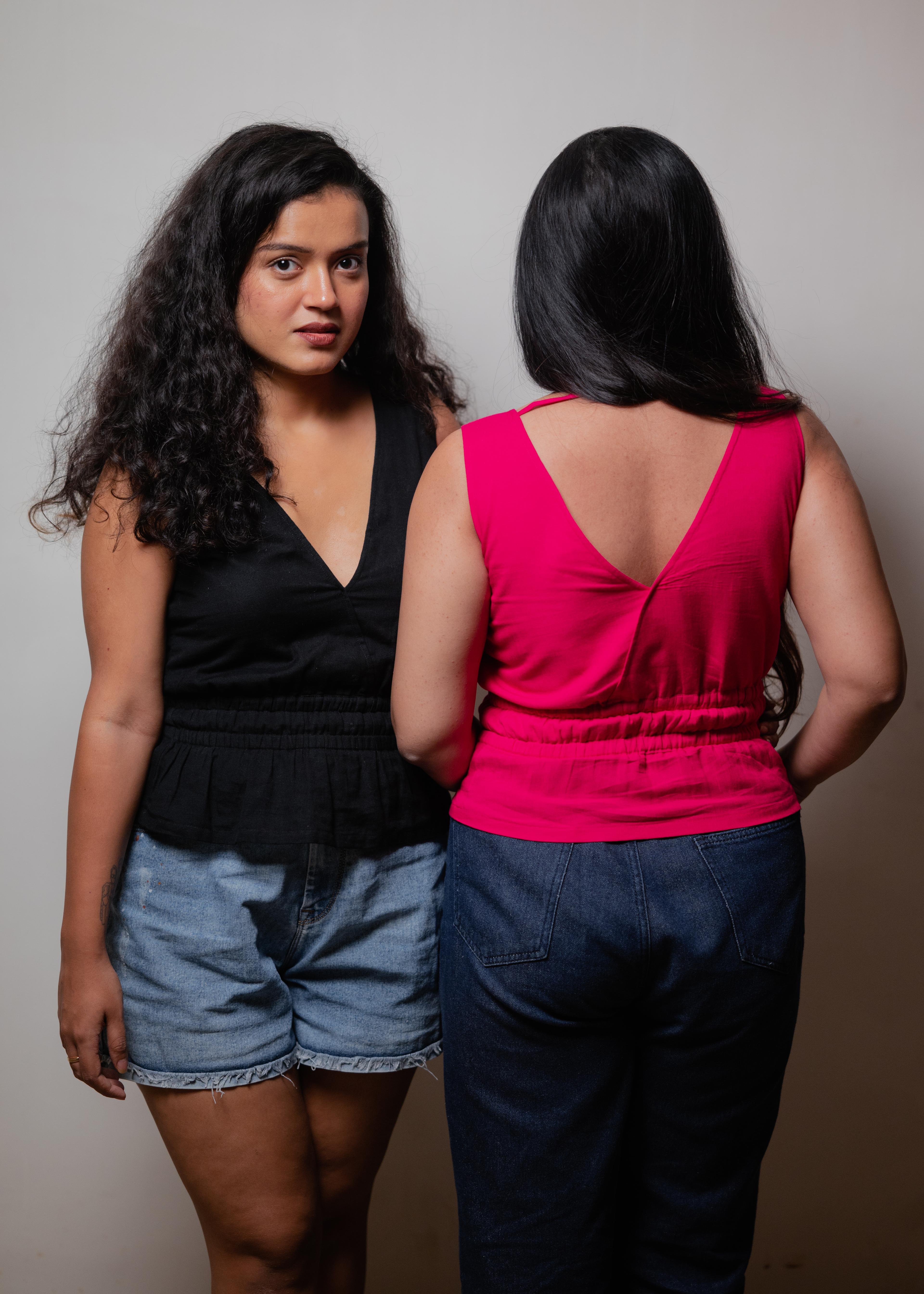 Two women of SAMAA in the black V-neck top and the pink V-neck top